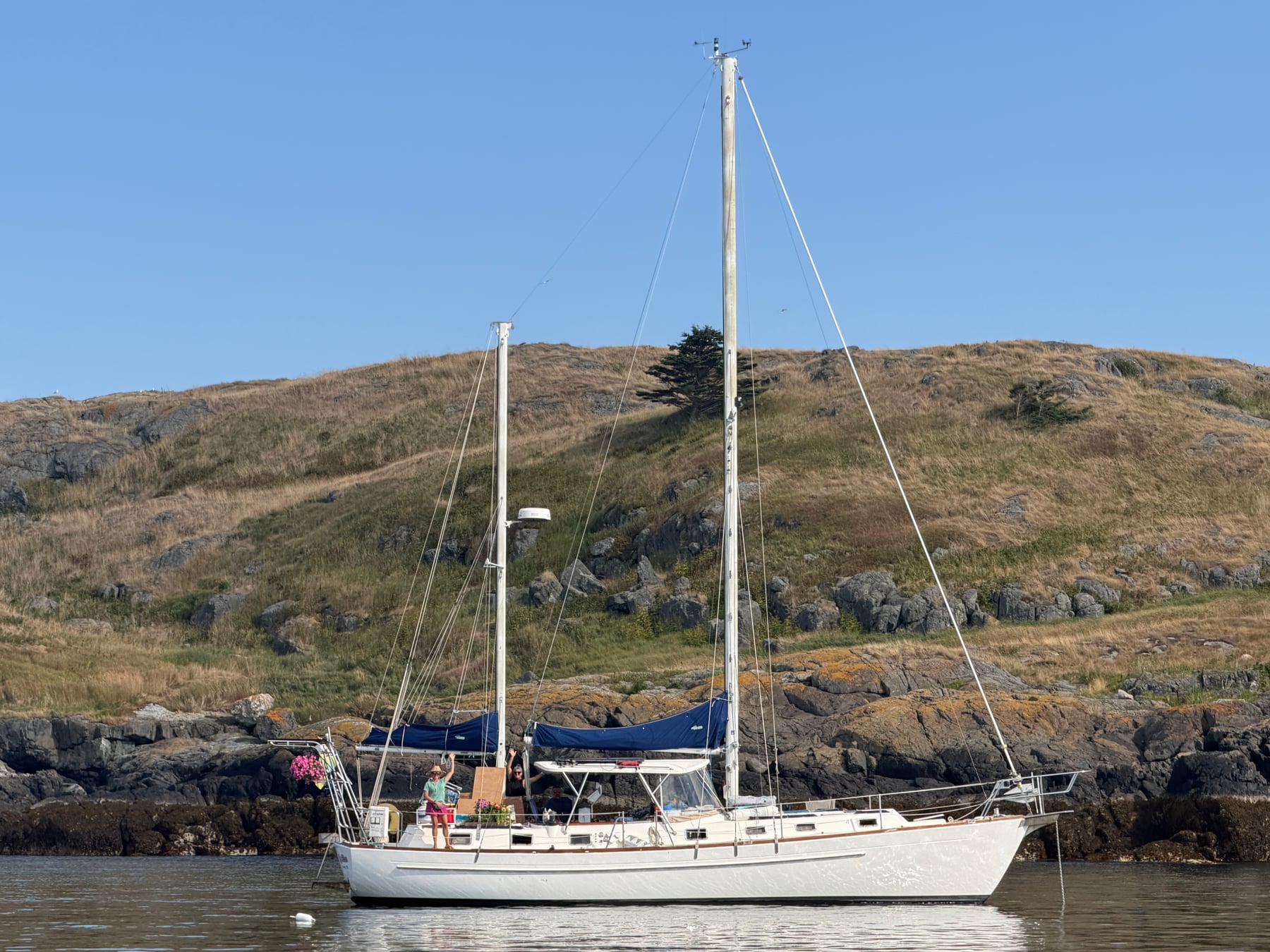 LuRu at anchor beside a rocky, grassy shore